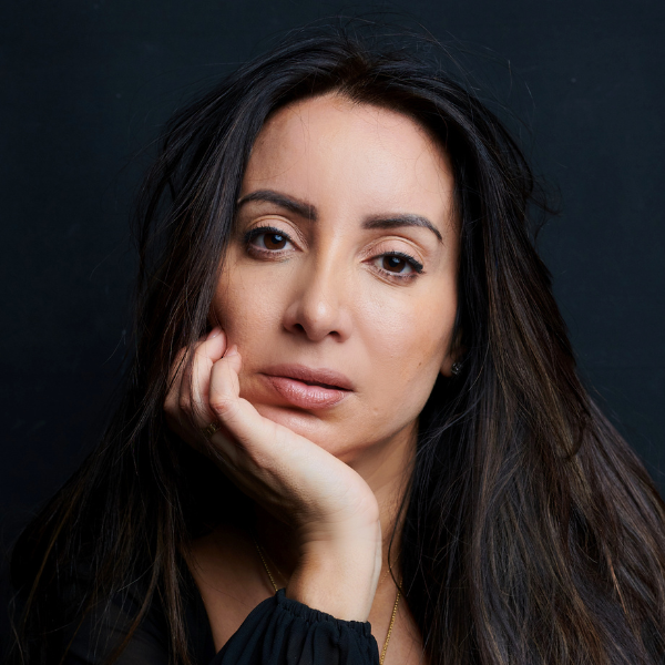Image of Antoinette Lattouf. She has long dark hair and is sitting with her chin on her hand.